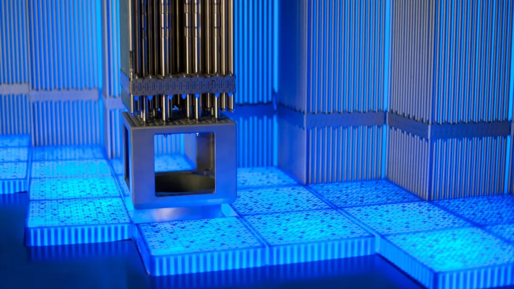 Conjunto de combustible nuclear iluminado con luz azul intensa en el interior de un reactor.