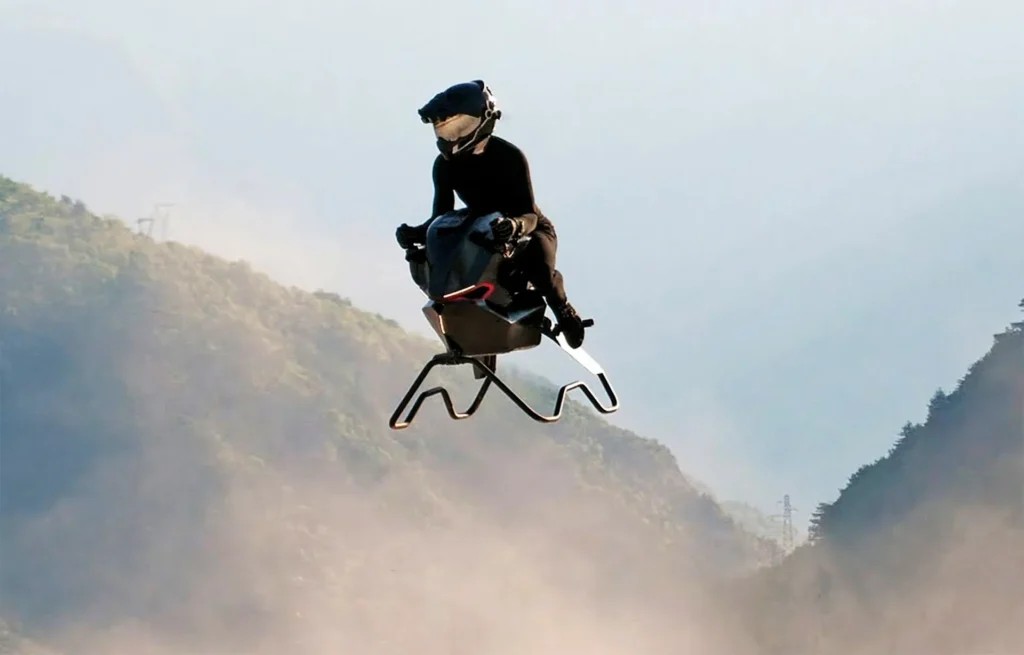 Persona pilotando la Airbike voladora de Volonaut sobre un valle montañoso, con polvo levantado por el impulso del movimiento.