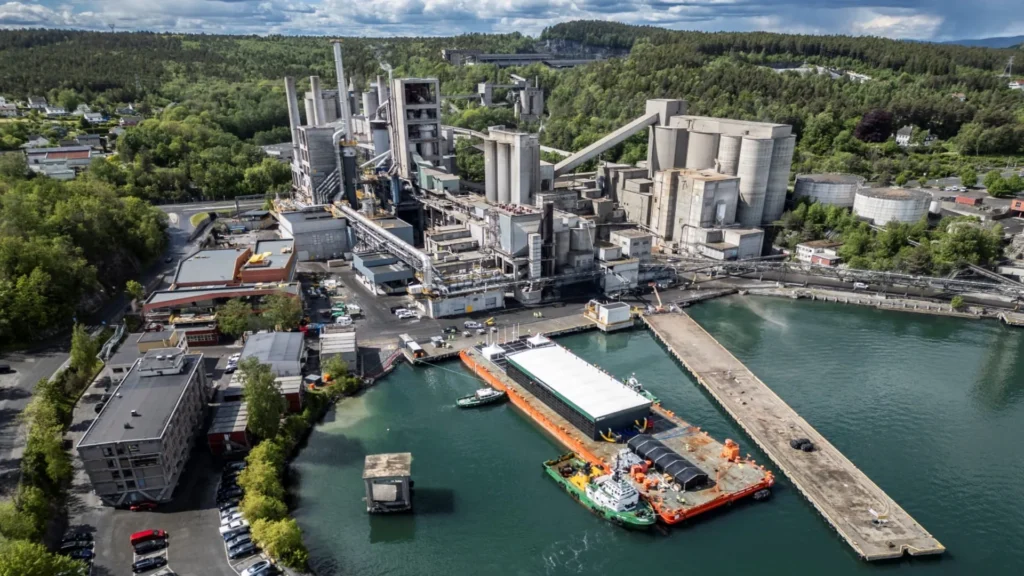 Vista aérea de la planta Brevik CCS de Heidelberg Materials en Noruega, con instalaciones industriales y un muelle con embarcaciones para transporte de CO₂.