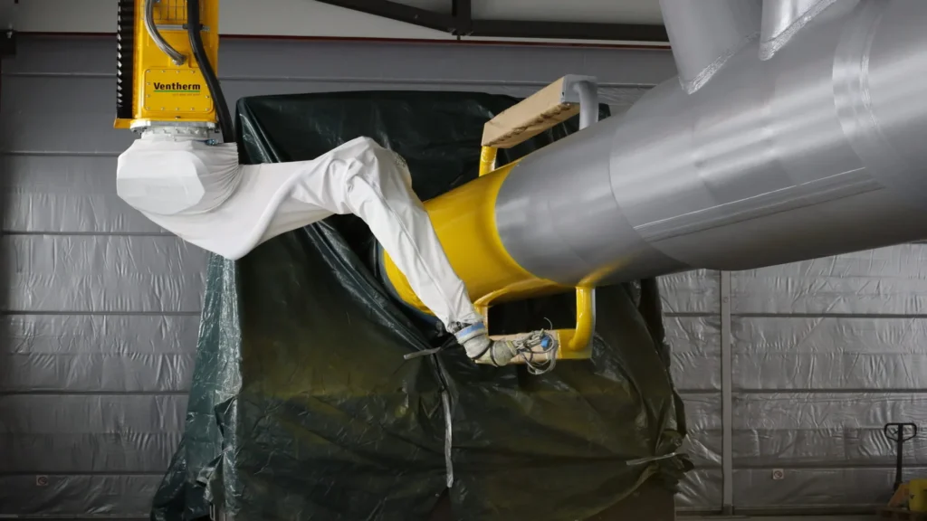 Sistema de automatización robótica Ventherm aplicando pintura a una estructura metálica de gran tamaño en un entorno industrial.