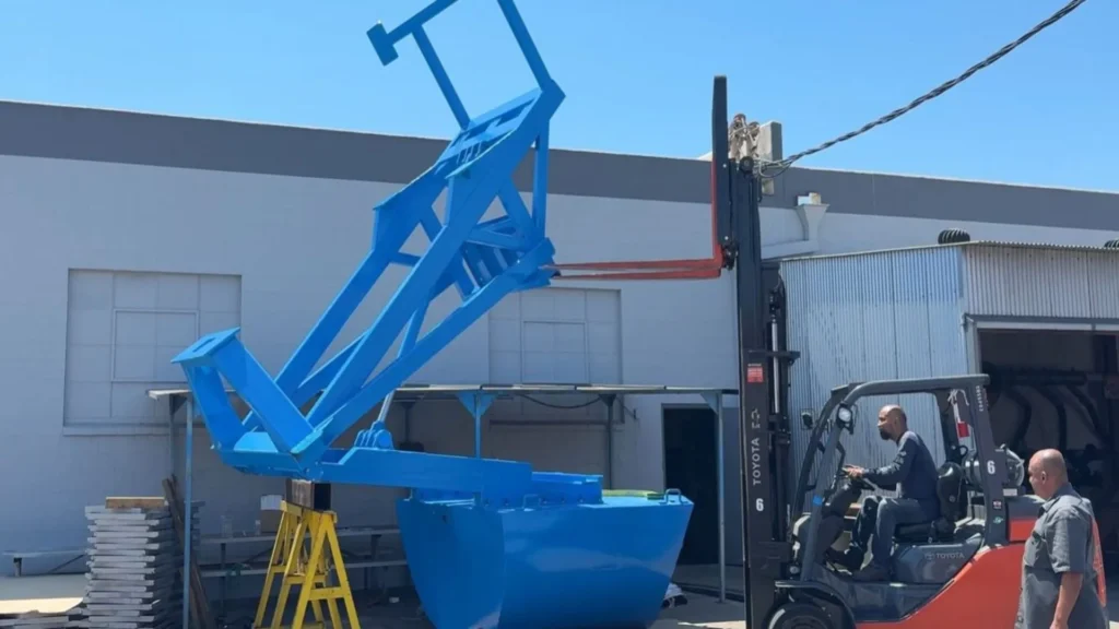 Trabajadores maniobrando con montacargas un flotador azul de energía undimotriz en las instalaciones de C&S Welding en California.