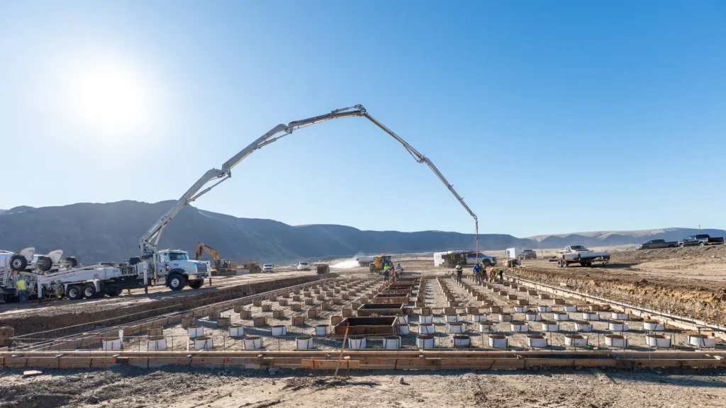 Obreros y maquinaria vacían concreto en los cimientos de la planta de energía de fusión Orion de Helion Energy en un terreno desértico de Washington.