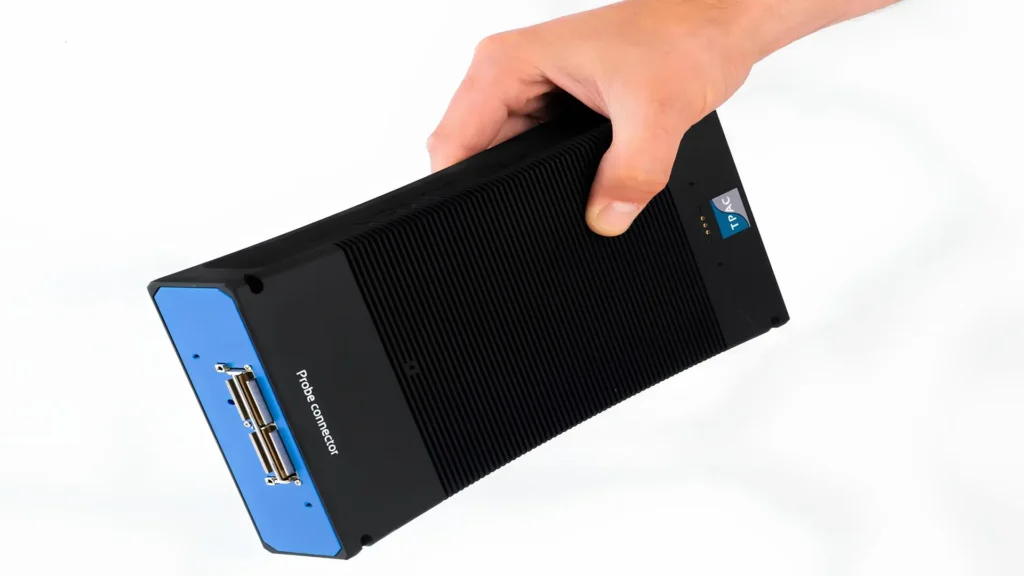 Person holding TPAC's Explorer equipment, a compact phased array ultrasound device used for non-destructive industrial inspections.