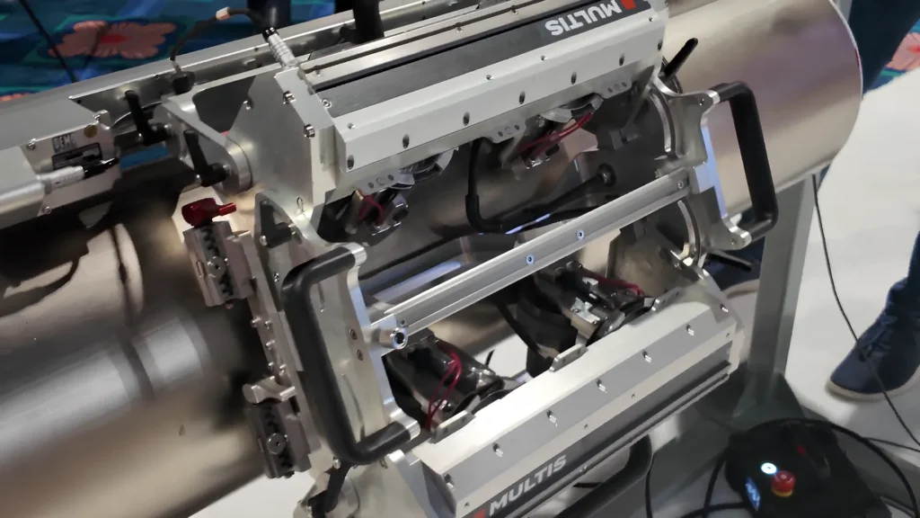 Primer plano del robot de inspección industrial Multis de JIREH Industries, montado sobre una tubería metálica durante una demostración técnica en el evento ASNT 2025.