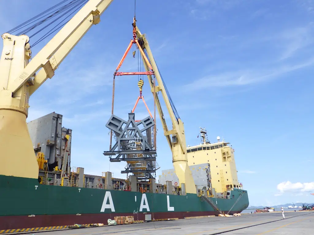 Grúa embarcando una estructura metálica pesada sobre el buque AAL Bangkok durante una operación de carga industrial en puerto.