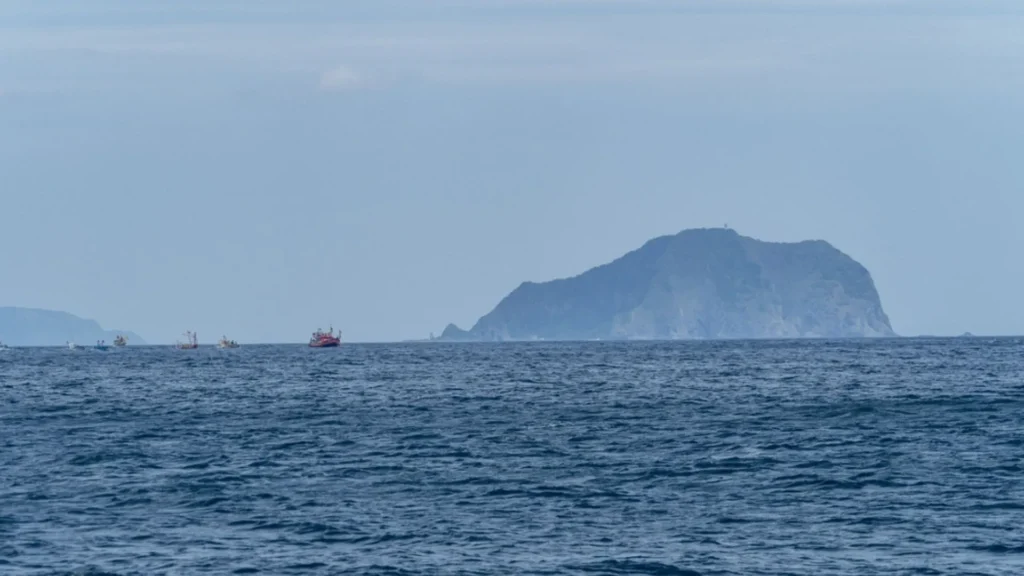 Barcos pesqueros en el Mar del Norte navegando cerca de una isla, en el contexto del Plan de Futuro del Mar del Norte.