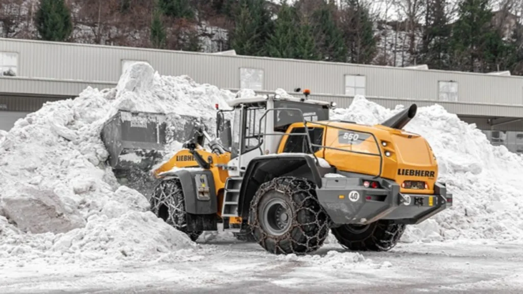 Cargadoras de ruedas Liebherr 550 XPower removiendo nieve con cadenas en las ruedas durante una operación de limpieza invernal.