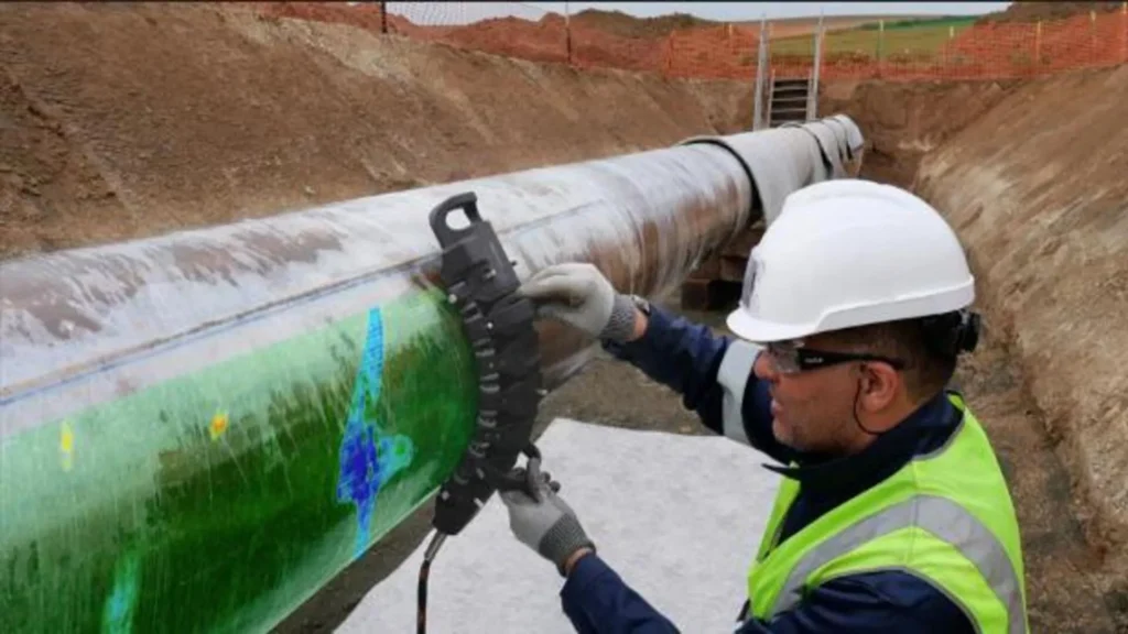 Técnico que realiza una inspección de grietas superficiales en una tubería utilizando el escáner Spyne™ con visualización de datos en tiempo real.