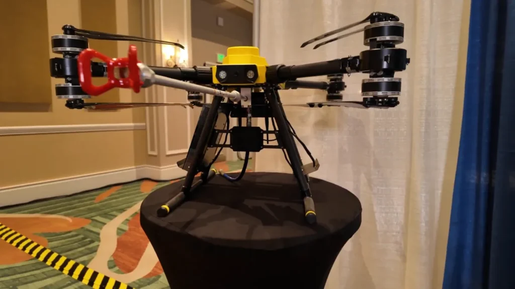 Drone de mantenimiento industrial con sistema de limpieza y recubrimiento sobre mesa de exhibici&oacute;n.