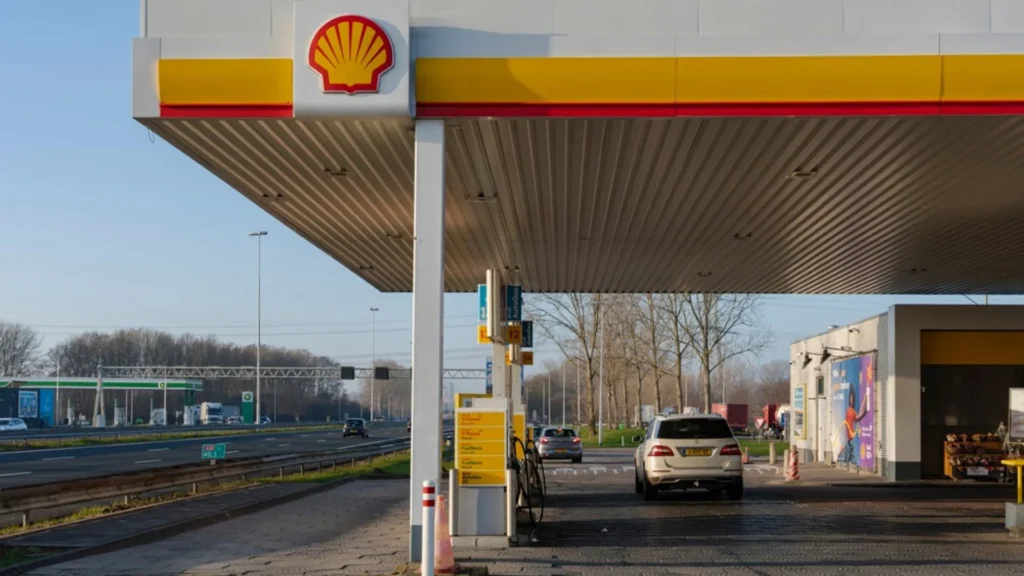 Estaci&oacute;n de servicio Shell junto a una carretera con veh&iacute;culos repostando combustible.
