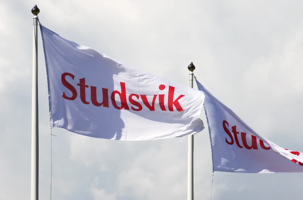 Studsvik flags flying against a cloudy sky at the company's facilities in Sweden.