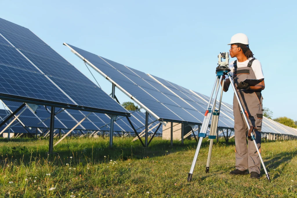 TotalEnergies impulsa la energ&iacute;a solar con un t&eacute;cnico inspeccionando paneles solares en un parque fotovoltaico.